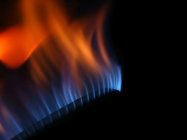 Niebiesko-pomarańczowy płomień nad palnikiem gazowym na czarnym tle