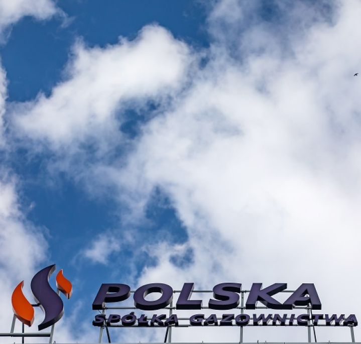 Logo PSG na dachu budynku, na tle niebieskiego nieba z chmurami
