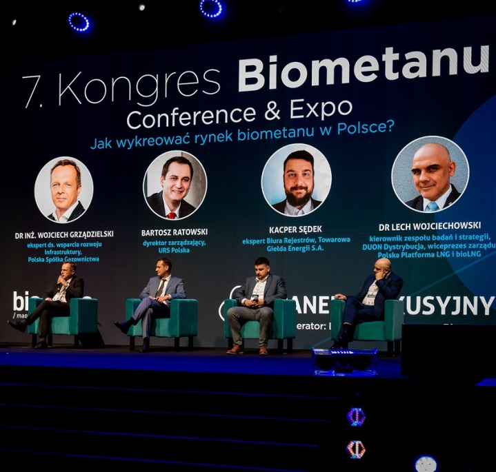 Uczestnicy panelu podczas 7. Kongresu Biometanu siedzą na fotelach na scenie i dyskutują, szeroki kadr, w tle ekran z wyświetlonymi zdjęciami panelistów