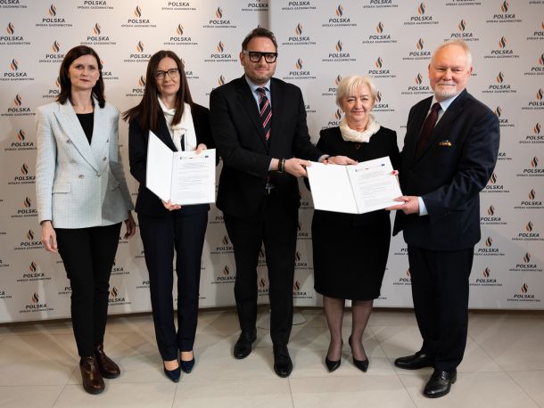 Pięciu uczestników konferencji prasowej prezentuje podpisaną umowę, w tle ścianka obrandowana logo Polskiej Spółki Gazownictwa