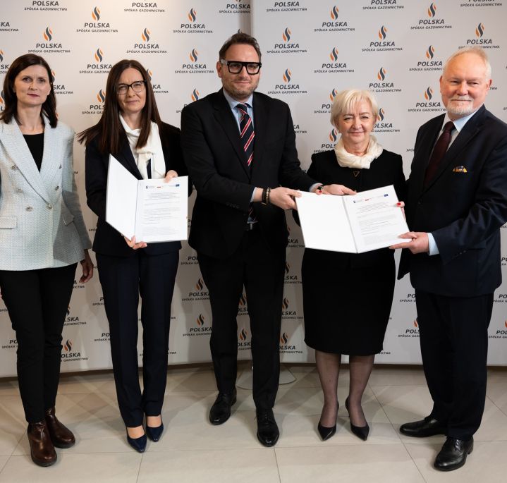 Pięciu uczestników konferencji prasowej prezentuje podpisaną umowę, w tle ścianka obrandowana logo Polskiej Spółki Gazownictwa
