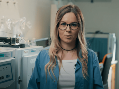Pracowniczka laboratorium jakości gazu, w tle urządzenia do badania jakości gazu