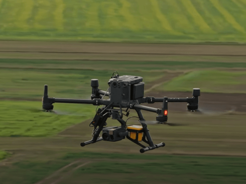 Czterowirnikowy dron PSG lecący nad zielonymi polami