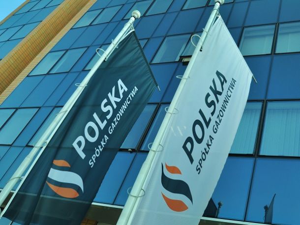 Flagi z logo Polskiej Spółki Gazownictwa na tle biurowca ze szklanymi ścianami