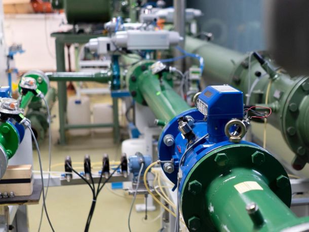 Inside the laboratory, green and blue pipes with numerous connected devices and cables between them.