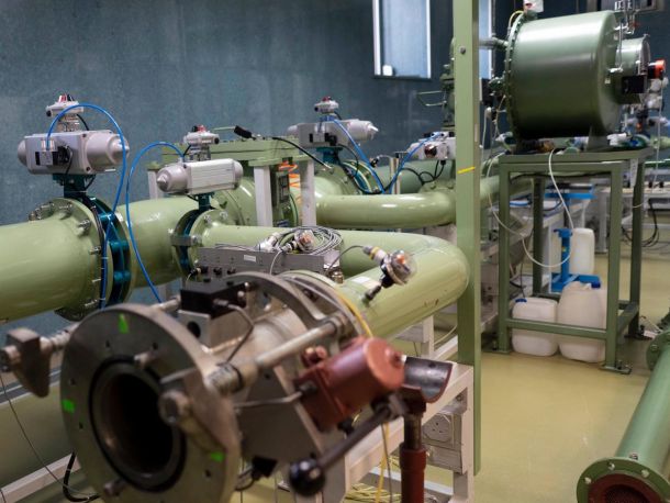 Wnętrze laboratorium, zielone rury z wieloma przyłączonymi urządzeniami i przewodami pomiędzy nimi