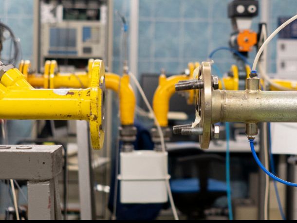 Wnętrze laboratorium, żółte rury zwrócone do siebie, widoczny gazomierz oraz liczne przewody