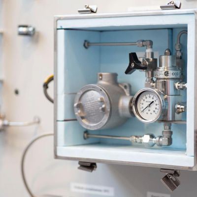Interior of a laboratory measuring box with a metal pressure gauge, valve and other components