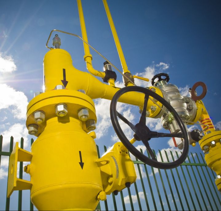Yellow gas infrastructure components (pipes, pressure gauge) against a backdrop of blue sky and sunshine