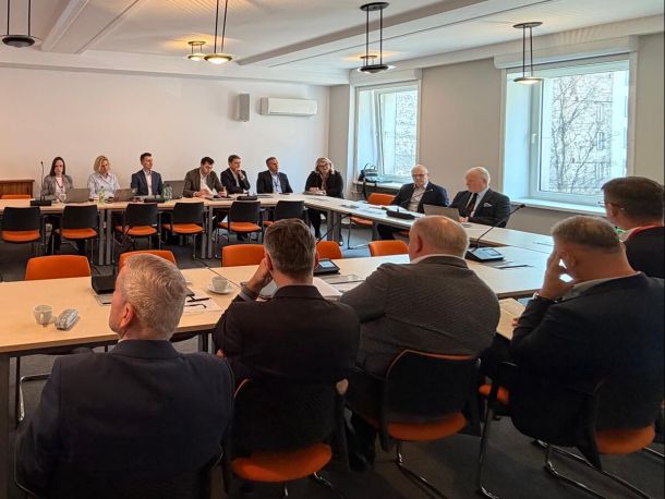 The participants in the meeting with the contractors are seated around a table in a conference-style layout