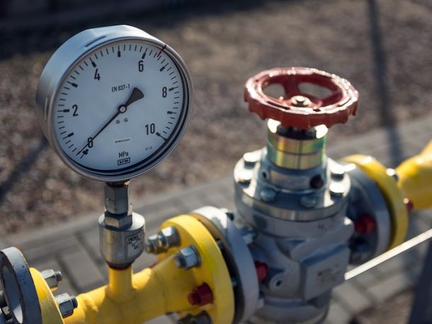 Gas infrastructure components: a pressure gauge with a red valve on a yellow pipe