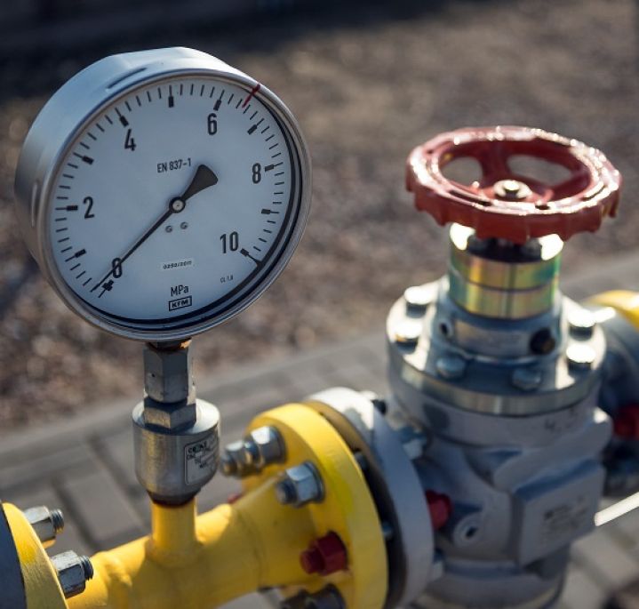 Gas infrastructure components: a pressure gauge with a red valve on a yellow pipe